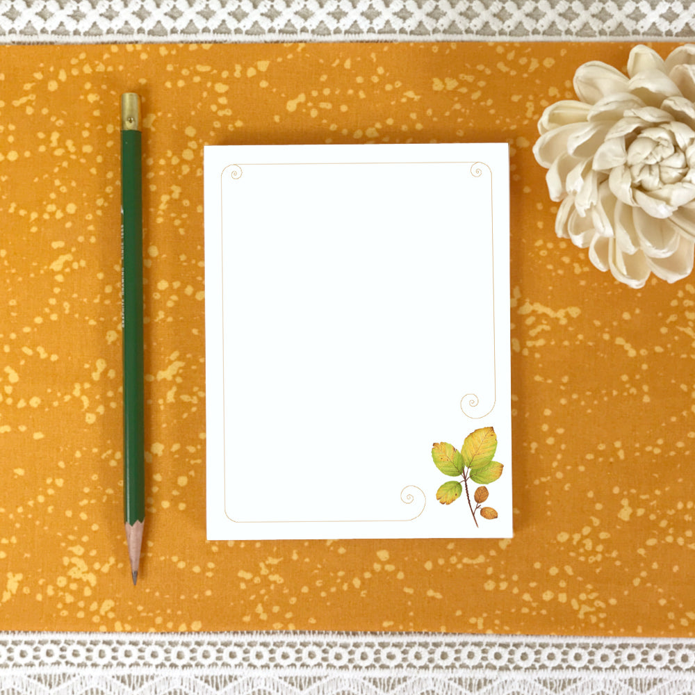 Unlined notepad with a watercolor autumn leaf in bottom right corner.