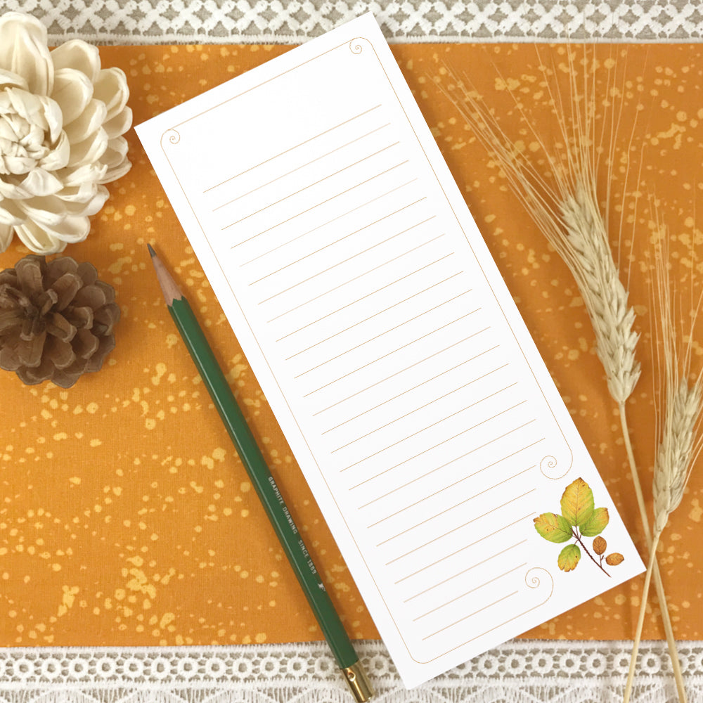 Tall lined notepad with watercolor autumn leaves in bottom right corner.